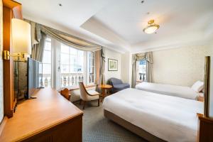 a hotel room with a bed and a desk and a bed and a window at KOKO HOTEL Osaka Shinsaibashi in Osaka