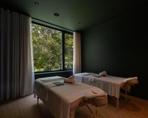 two beds in a room with a large window at Furnas Lake Forest Living in Furnas