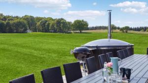 a table with chairs and a grill in a field at Villavilla 604 - Gjerrild, Østjylland in Grenå