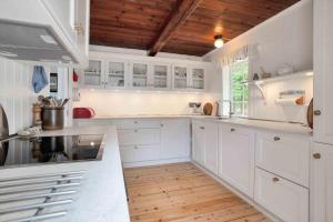 a white kitchen with white cabinets and wooden ceilings at 10081B-Rorvig-Skansehagevej-32 in Rørvig +15 photos