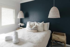 a bedroom with a white bed with two pendant lights at La Ronde Three - Unit 3 - Oceanstays in Yamba
