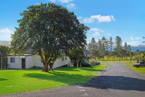 a house with a tree on the side of a road at Almare, 7 Gowing Street in Crescent Head