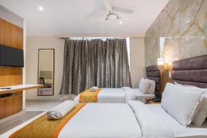 a hotel room with two beds and a television at The Orange Hotel in Visakhapatnam