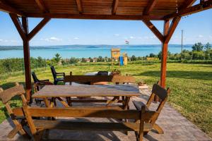 a picnic table with chairs and a view of the water at Ádám nyaralóház in Balatonalmádi +12 photos