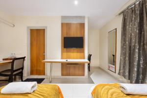 a room with two beds and a desk with a television at The Orange Hotel in Visakhapatnam