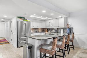 a kitchen with a refrigerator and a counter with chairs at Escape to Beach Oasis! Family Friendly, Updated Beachside Condo with Heated Pool! in Clearwater Beach