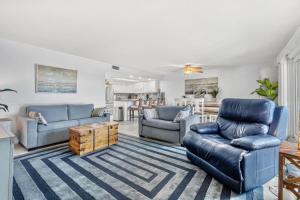 a living room with blue couches and a kitchen at Escape to Beach Oasis! Family Friendly, Updated Beachside Condo with Heated Pool! in Clearwater Beach