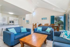 a living room with blue couches and a wooden table at Breakers 2 in Crescent Head