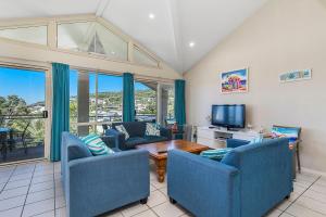 a living room with blue chairs and a television at Breakers 2 in Crescent Head