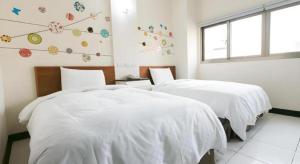 a bedroom with two beds with white sheets and a window at E Moon Hotel in Taichung +46 photos