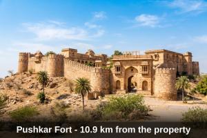 a castle on a hill with palm trees in front of it at Hotel O Parao Formerly Cozy Inn in Ajmer