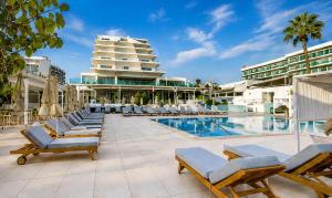 a swimming pool with lounge chairs and a hotel at Vrissiana Boutique Beach Hotel in Protaras