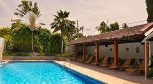 a swimming pool with chairs next to a building at Marcosas Cottages Resort in Basdiot