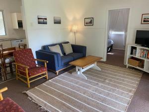 a living room with a blue couch and a table at Fleur Cottage, 7 Willow Street in Crescent Head +5 photos