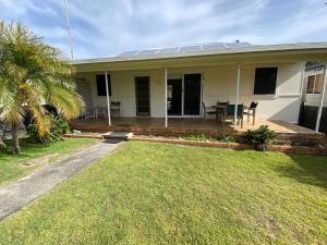 a white house with a lawn in front of it at Fleur Cottage, 7 Willow Street in Crescent Head