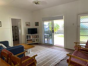 a living room with a couch and a tv at Fleur Cottage, 7 Willow Street in Crescent Head