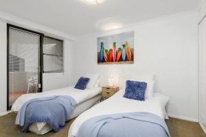 two beds in a white room with a painting on the wall at Flightdeck 101, Clarence Street in Port Macquarie +6 photos