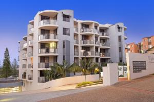 a tall white building with palm trees in front of it at Flightdeck 101, Clarence Street in Port Macquarie