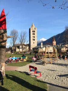 un parque infantil frente a un edificio con una torre en Alloggio turistico Maison S Anselme VDA Aosta CIR 0015, en Aosta