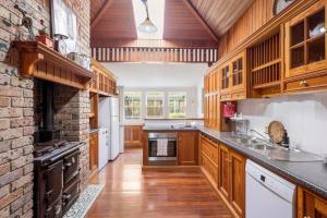 a kitchen with wooden cabinets and a brick wall at Historic Huntingdon House in Wauchope
