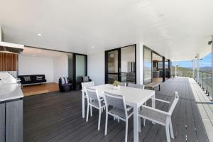 a kitchen and dining room with a white table and chairs at La Mer, 19 Dulconghi Street in Crescent Head +13 photos