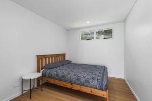 a bedroom with a bed and a stool and a window at La Mer, 19 Dulconghi Street in Crescent Head