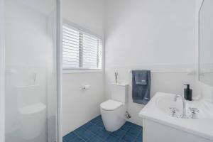 a white bathroom with a toilet and a sink at Lighthouse Beach Luxury in Port Macquarie +16 photos