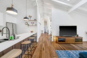 a kitchen and living room with a large flat screen tv at Lighthouse Beach Luxury in Port Macquarie