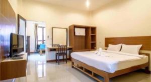 a bedroom with a bed and a desk and a television at Cindia Resort in Phun Phin