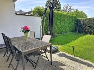 a table with a vase of flowers and an umbrella at Holiday Home Ruiterlaan with parking by Interhome in Bredene