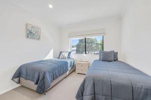 two beds in a white room with a window at Pippies, your water view escape in North Haven
