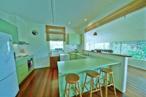 a kitchen with a counter and stools in it at Rosemaree, 24 East Street in Crescent Head +8 photos
