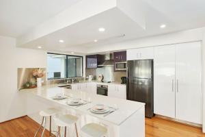 a kitchen with white cabinets and a large island with stools at Riverside Luxury in Port Macquarie