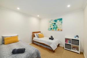 a bedroom with two beds and a book shelf at Riverside Luxury in Port Macquarie