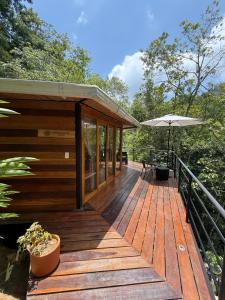 a wooden deck with a bench and an umbrella at SeTena Tierra Humeda Ecolodge in Minca