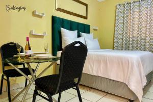 a hotel room with a bed and a table with two chairs at Budget Stays at Olivia Pines Guesthouse in Krugersdorp