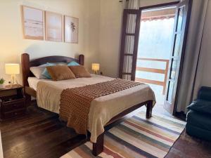a bedroom with a bed and a large window at Duplex 450m da Praia do Peró, Roupa Cama e Banho, Wi-Fi, TV a Cabo, Estacionamento in Cabo Frio