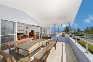 a house with wooden benches on a balcony at Vaka Malua, 7 Scott Street in Crescent Head