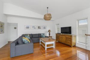 a living room with a couch and a tv at Vaka Malua, 7 Scott Street in Crescent Head