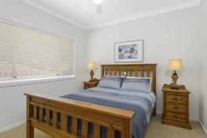 a bedroom with a wooden bed and a window at Vaka Malua, 7 Scott Street in Crescent Head