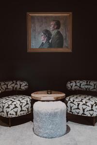 a living room with two chairs and a table and a painting at Aktiv & Spa Hotel Alpenrose in Schruns