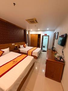 a hotel room with two beds and a television at Chu Long Hotel & Spa in Cat Ba
