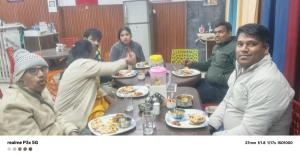 a group of people sitting around a table eating food at Hotel Kalyan Palace And Restaurant in Pīpalkoti