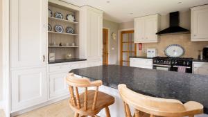 a kitchen with white cabinets and a black counter top at Kingfisher Cottage in Winchcombe +20 photos