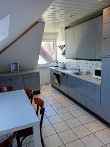 a kitchen with gray cabinets and a white table with chairs at Zimmervermietung Weitblick in Burgdorf
