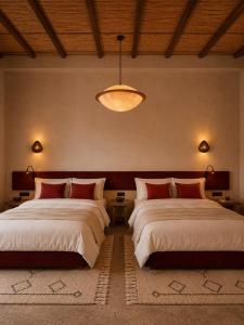 a bedroom with two beds and a chandelier at TIZI Aït Ben Haddou in Aït Benhaddou