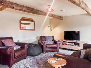 a living room with leather furniture and a flat screen tv at Holme House in Halton Gill