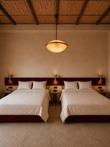 a bedroom with two beds and a chandelier at TIZI Aït Ben Haddou in Aït Benhaddou