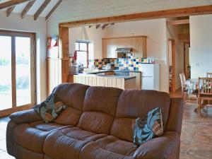 a brown couch in a living room with a kitchen at Meadow Cottage - Uk45882 in Flamborough