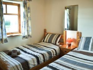 a bedroom with two beds and a mirror and a window at Meadow Cottage - Uk45882 in Flamborough